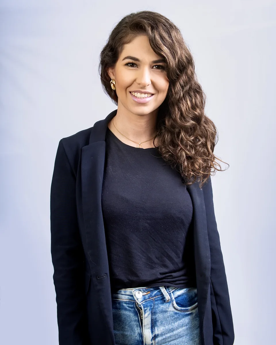 Bruna Gelbcke, arquiteta, sorrindo, de blazer azul-marinho